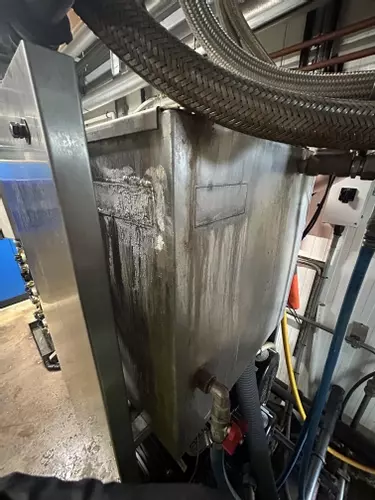 Original leaking water tank on Nilfisk Delta Booster multi-pump pressure washer system before replacement.